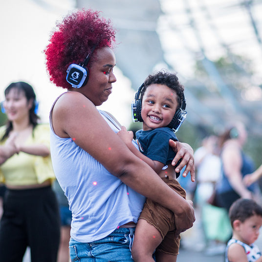 Quiet Events Silent Disco headphones for all ages; a mother and baby son held together enjoying and having fun with headphones.