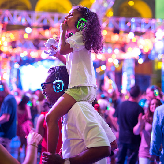 Quiet Events Silent Disco headphones for all ages. A father with her daughter on his shoulders at a festival having fun.