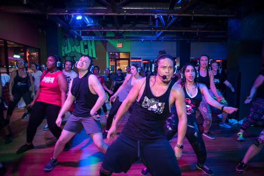 Quiet Events Silent Disco headphones for all ages. A group of gym members taking a dance class with an instructor ahead of the class.