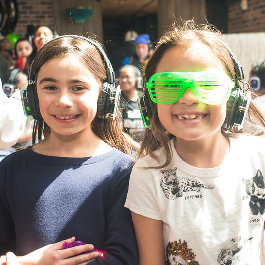 Quiet Events Silent Disco headphones for bar mitzvah. Two young little girls having fun and smiling wearing headphones.