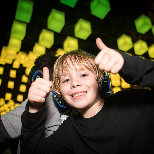 Quiet Events Silent Disco headphones for bar mitzvah. A young boy posing for a picture with two thumbs up and wearing headphones.