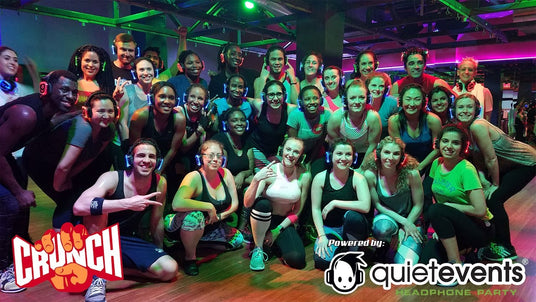 Quiet Events Silent Disco headphones for fitness. A group of people posing after an aerobics class wearing headphones.