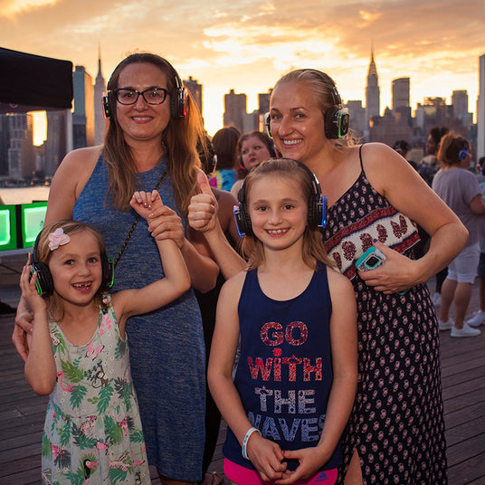 Quiet Events Silent Disco headphones for fund raising. Two mothers and their children at an outdoor event having fun with headphones.