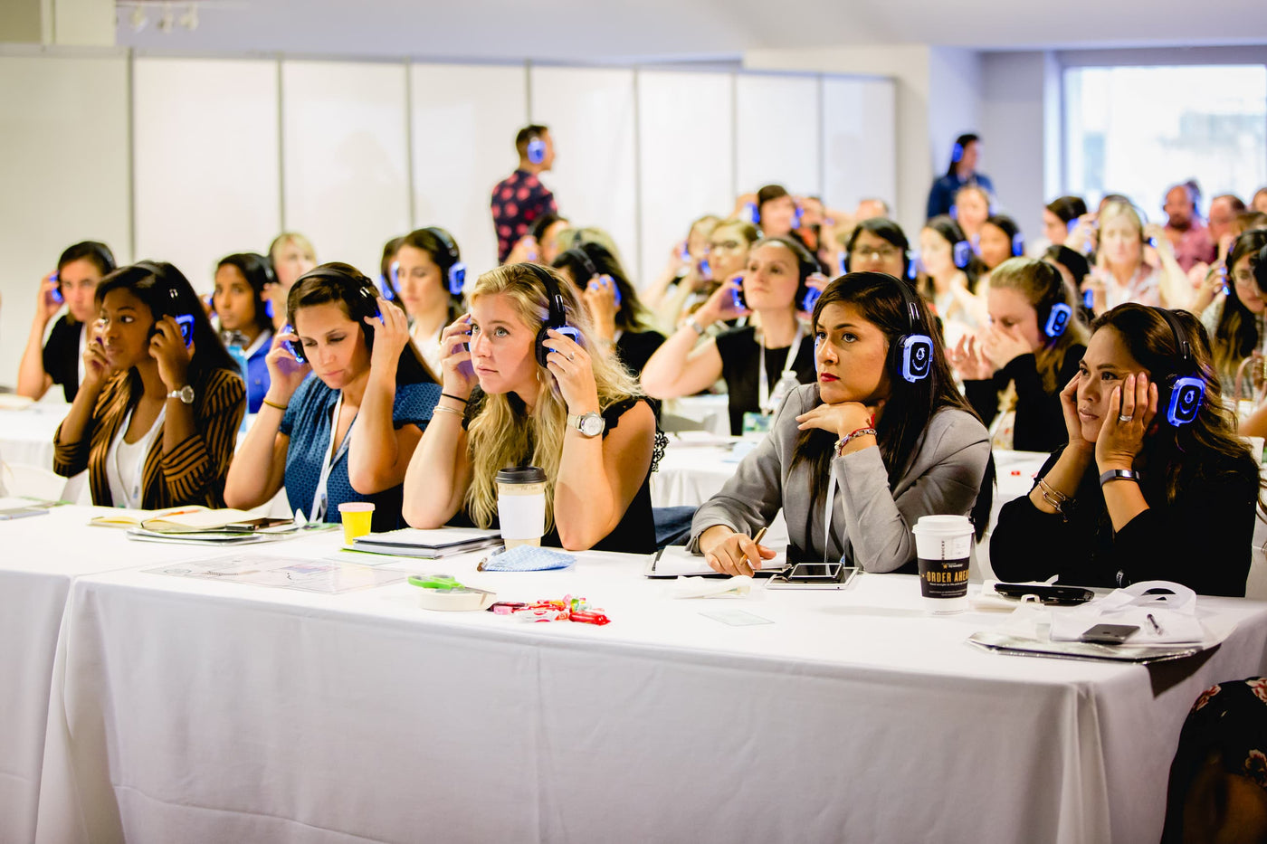 Quiet Events Silent Disco headphones for meetings a group of women wearing headphones sitting and listening to a speaker.