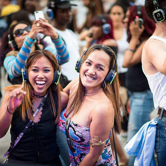 Quiet Events Silent Disco headphones for public spaces two young girls smiling and having fun with headphones.