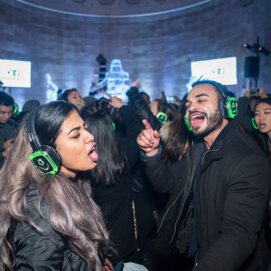 Quiet Events Silent Disco headphones for public spaces a couple singing and dancing in an open space with headphones