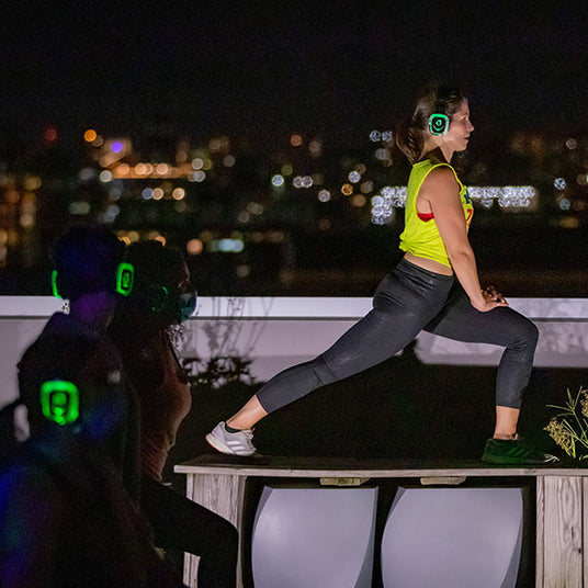 Quiet Events Silent Disco headphones for yoga. A yoga instructor on a podium teaching a class at night.