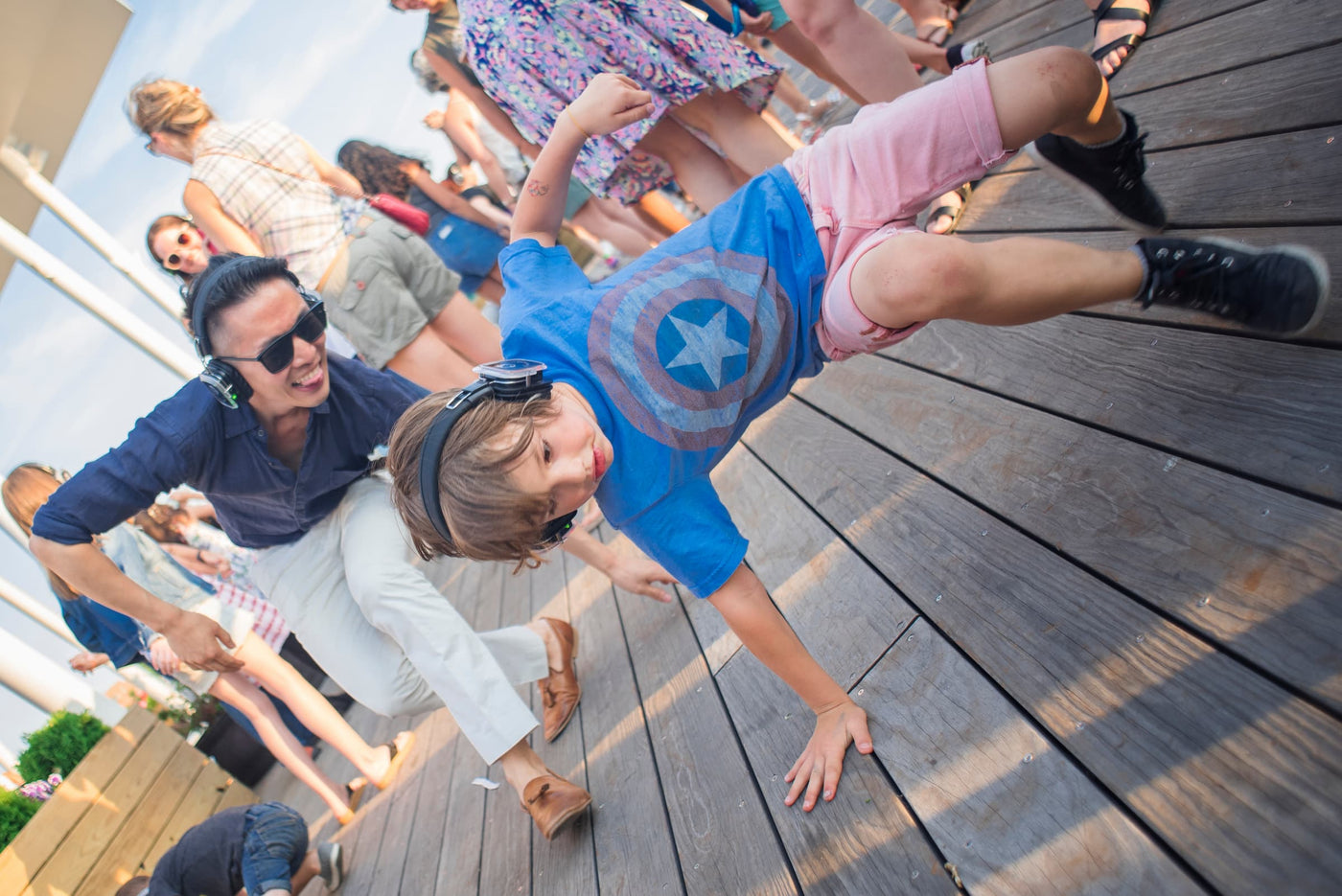 Quiet Events Silent Disco headphones for bar mitzvah.  A young boy breakdancing in front of group of adults.
