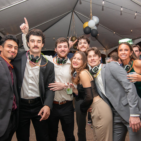 Quiet Events Silent Disco headphones for corporate.  A group of professionals together posing for a picture at a party with headphones.