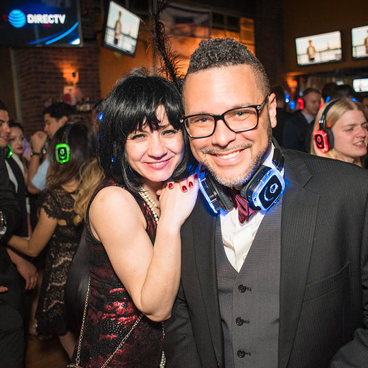 Quiet Events Silent Disco headphones for corporate party.  A professional couple posing in the middle of the floor with headphones.