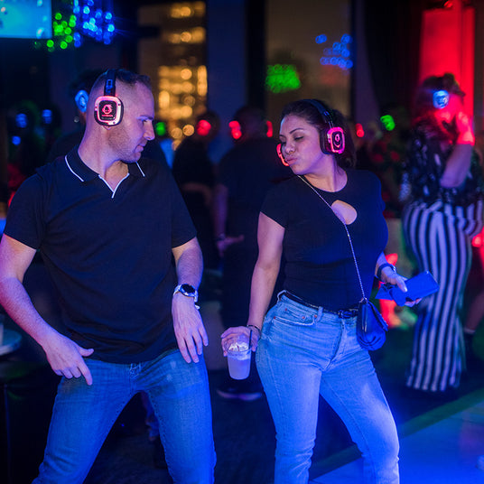 Quiet Events Silent Disco headphones for corporate party.  A couple on the dance floor having fun with headphones.