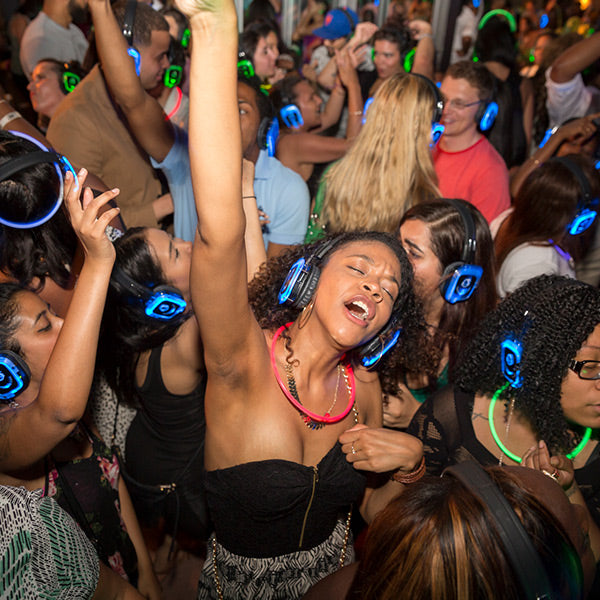 Quiet Events Silent Disco headphones for dance parties a group of people dancing wearing headphones singing along.