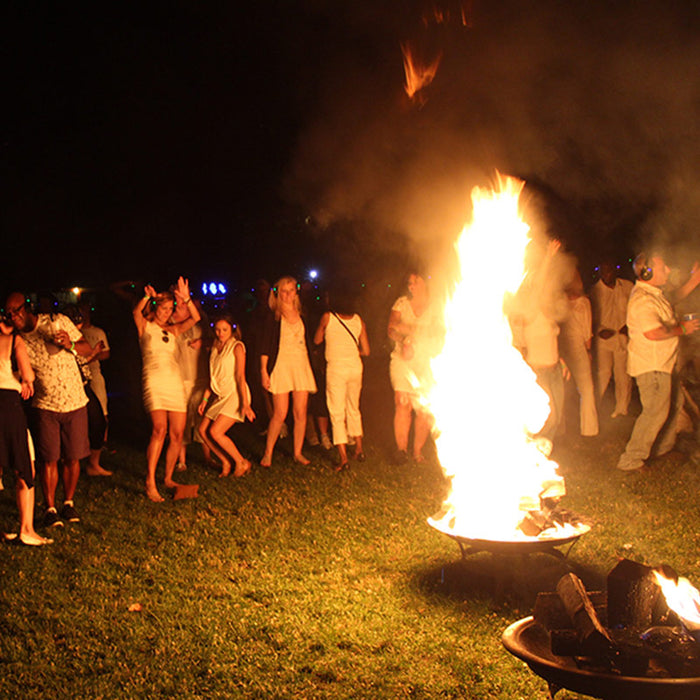 Quiet Events Silent Disco headphones for dance parties at a camp ground at night with a bon fire dancing around it with headphones.