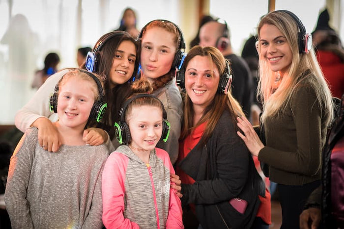 Quiet Events Silent Disco headphones for dance parties a group of young girls with headphones having fun and smiling.