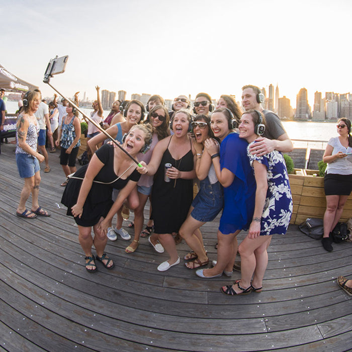 Quiet Events Silent Disco headphones for dance parties a group of people at a park taking a selfie with headphones