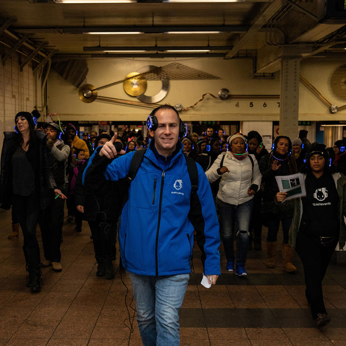 Quiet Events Silent Disco headphones for run and walks. A group of people marching having fun in the subway halls with headphones listening to music.